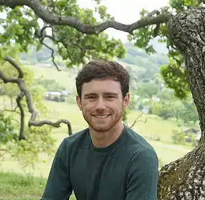 Young man outdoors with nature background, promoting awareness of eating disorders and resources.