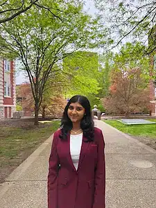 Young woman standing outdoors in university campus with trees, promoting awareness of eating disorders and support.