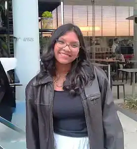 Young woman smiling at a cafe promoting eating disorder awareness and recovery.